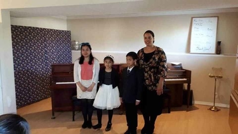 Students and Instructor standing in front of the piano