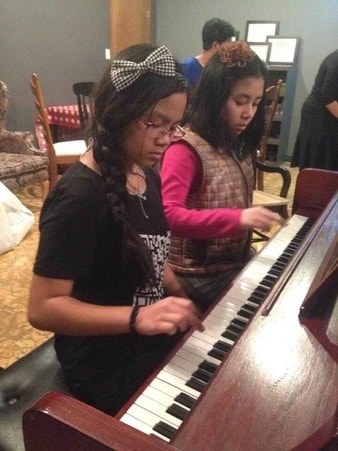 Erica and Niobe playing the acoustic piano